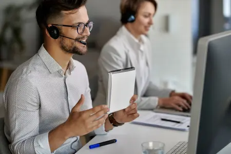 Eine glückliche Kundendienstmitarbeiterin führt ein Videogespräch mit Kunden während der Arbeit im Callcenter.